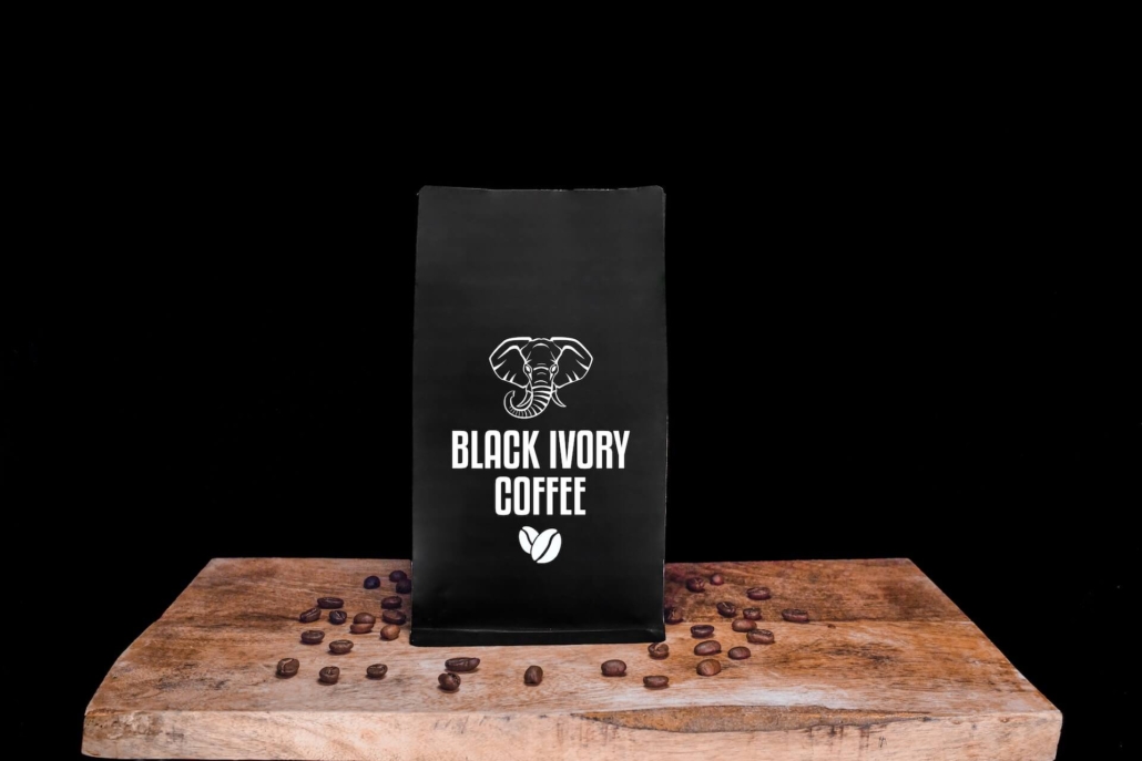 Black Ivory Kaffeebohnen und Verpackung auf einem Holzbrett